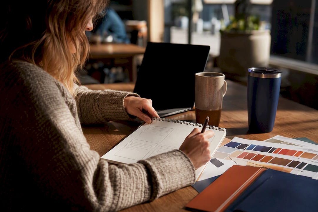 Hands sketching travel website layout on desk