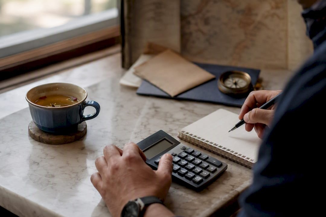 Hands calculating commission at travel agent desk
